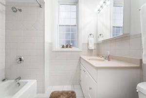 a white bathroom with a tub and a sink and a bath tubermott at The Wrigleyville VIP-200 Steps from Wrigley Field in Chicago