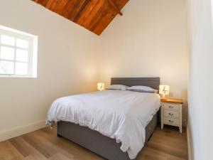 a white bedroom with a bed and a window at Swallow Cottage in Sandbach