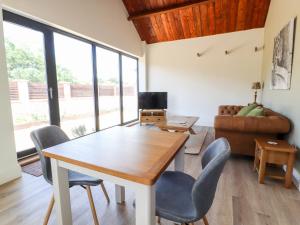 sala de estar con mesa, sillas y sofá en Swallow Cottage en Sandbach