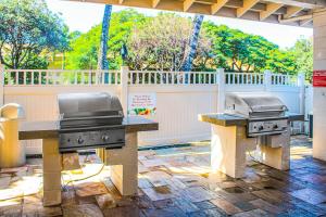 two grillfires on a patio with a fence at Kihei Akahi in Wailea
