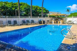a large swimming pool with chairs and a fence at Kihei Akahi in Wailea