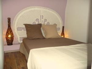 a bedroom with a bed with a white headboard and lights at Bed and Breakfast Jardin de Marie in Aix-en-Provence