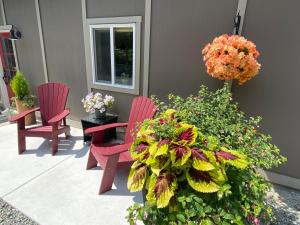 two red chairs sitting on a porch with flowers at Hardy’s Haven in North Saanich