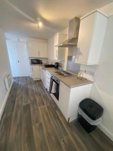 a kitchen with white cabinets and a wooden floor at Spacious 1 Bedroom Apartment with free parking in Wednesbury