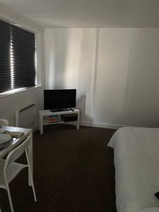 a bedroom with a bed and a table and a tv at Spacious 1 Bedroom Apartment with free parking in Wednesbury