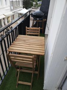uma mesa de madeira e 2 cadeiras numa varanda em Appartement Chez Bernadette à 50m de la plage em Saint-Cast-le-Guildo