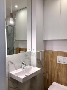 a white bathroom with a sink and a mirror at Apartament Szpitalna in Poznań +10 photos