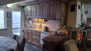 a kitchen with wooden cabinets and a table with chairs at Кошарите Стражата in Tsŭrvenyano