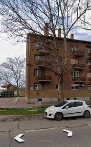 biały samochód zaparkowany przed budynkiem w obiekcie Fürdő Apartman w mieście Makó