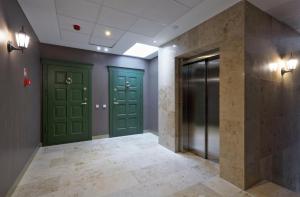 a hallway with green doors and a tile floor at Modern studio in bohemian Uzupis, Vilnius in Vilnius