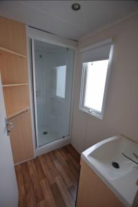 a bathroom with a shower and a sink and a window at Mobil-Home Camping de la dune Blanche in Camiers