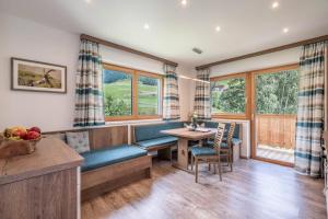 een woonkamer met een bank, een tafel en ramen bij Apart ALP in Kals am Großglockner
