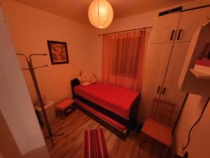 a small room with a red bed and a lamp at Studenac Mionica 