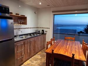 a kitchen with a wooden table and a large window at Cabañas Urmeneta Sur in Tongoy