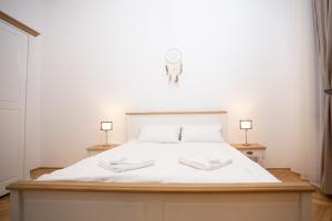 een slaapkamer met een groot wit bed met 2 lampen bij Heart of the city in Braşov