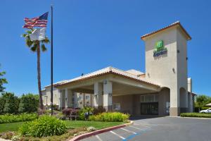 a hotel with a flag in front of a building at Holiday Inn Express Madera, an IHG Hotel in Madera
