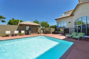 a swimming pool with chairs and a house at Holiday Inn Express Madera, an IHG Hotel in Madera