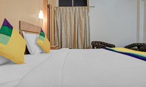 a bedroom with a white bed with colorful pillows at Itsy By Treebo - Ranjeet in Kolhapur