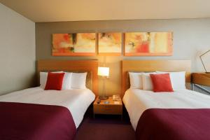 ein Hotelzimmer mit 2 Betten mit roten und weißen Kissen in der Unterkunft Camino Real Santa Fe in Mexiko-Stadt