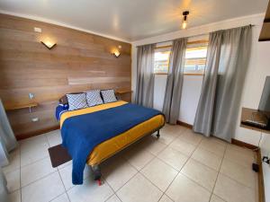 a bedroom with a bed with a wooden wall at Cabaña Clásica - BBQ Cocina Estacionamiento Wifi in Quintay