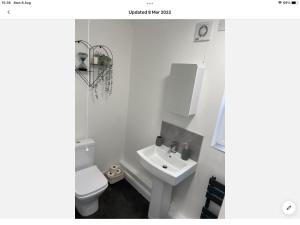 a white bathroom with a toilet and a sink at The Hilton Suite in Smalley
