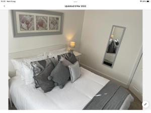 a bedroom with a white bed with pillows and a mirror at The Hilton Suite in Smalley