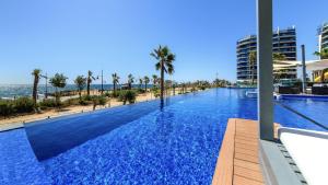 a large swimming pool with palm trees and a beach at Apartamento Sea Senses in Torrevieja