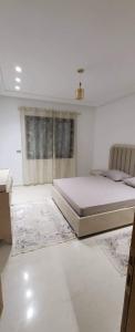 een witte slaapkamer met een bed en een raam bij Riadh Andalous: Superbe S+2 in Ariana