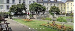 a park with benches and flowers in front of buildings at Admiral Hotel in Scarborough