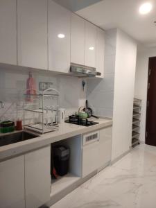 a kitchen with white cabinets and a sink and a counter at Precious Angel Apartment Sky House BSD in Pagedangan