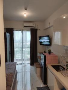a living room with a large window and a television at Precious Angel Apartment Sky House BSD in Pagedangan