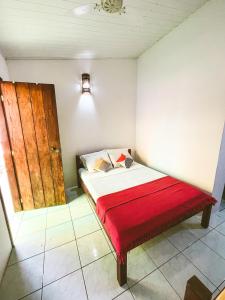 Habitación pequeña con cama con manta roja en Buddy's Hostel Itacaré, en Itacaré