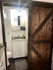 a bathroom with a wooden door and a toilet at Fox Tiny Home - The Cabins at Rim Rock in Austin