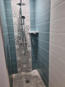 La salle de bains est pourvue d'une douche avec du carrelage bleu. dans l'établissement Gite de la Courtoisie, à Gavray
