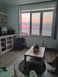 Appartement Cosy في أولت: غرفة معيشة مع طاولة وإطلالة على المحيط