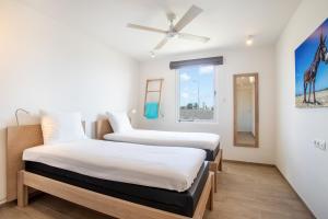 two beds in a room with a window at Chogogo Dive & Beach Resort Bonaire in Kralendijk