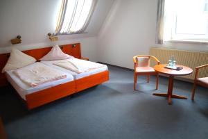 a bedroom with a bed and a table and a chair at Pension Zur Harburg in Uslar