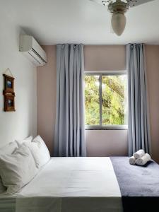 Un dormitorio con una cama grande y una ventana en Pousada Figueira, en Guarda do Embaú