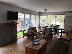 ein Wohnzimmer mit einem Sofa, Stühlen und einem TV in der Unterkunft Merland Park Cottages and Motel in Picton