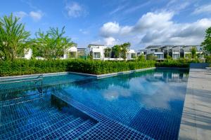 a swimming pool with blue tiles in front of houses at Laguna Park Villa with rooftop pool by Lofty in Bang Tao Beach