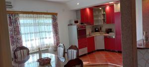 una cocina con armarios rojos y una mesa con sillas. en Guest House Enis en Dubrave Gornje