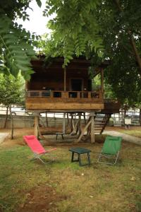 Tres sillas y una casa en el árbol en un parque en Saklı Cennet Bungalow & Tatil Köyü, en Çarşıbaşı