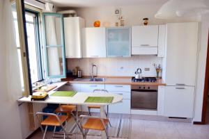 una cucina con mobili bianchi, tavolo e sedie di [Centro storico] Vulcano1, Bilocale strategico tra Milano, Como, fiere a Turate