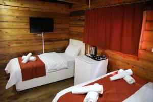 a bedroom with two beds and a television in a cabin at Saklı Cennet Bungalow & Tatil Köyü in Çarşıbaşı