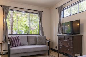 - un salon avec un canapé, une télévision et une fenêtre dans l'établissement Mackenzie Beach Resort, à Tofino