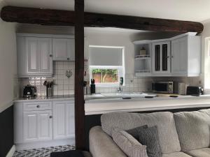 a kitchen with white cabinets and a couch at THE GARDEN SUITE in Denby