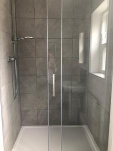 La salle de bains est pourvue d'une douche avec une porte en verre. dans l'établissement THE GARDEN SUITE, à Denby