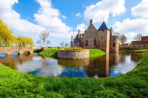 a castle with a river in front of it at Vakantiehuis in het hart van Medemblik in Medemblik