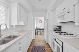 a white kitchen with a sink and a stove at Newport Coastal Comfort in Newport Beach +6 photos