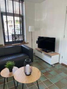 a living room with a couch and two tables at Vakantiehuis in het hart van Medemblik in Medemblik